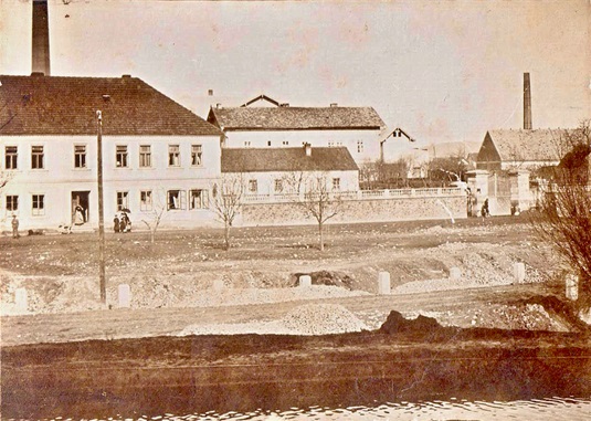 Náměstí Osvoboditelů číslo popisné 21. Vjezd do bývalé cementárny (dnes městský úřad). Vpředu potok (1905)
